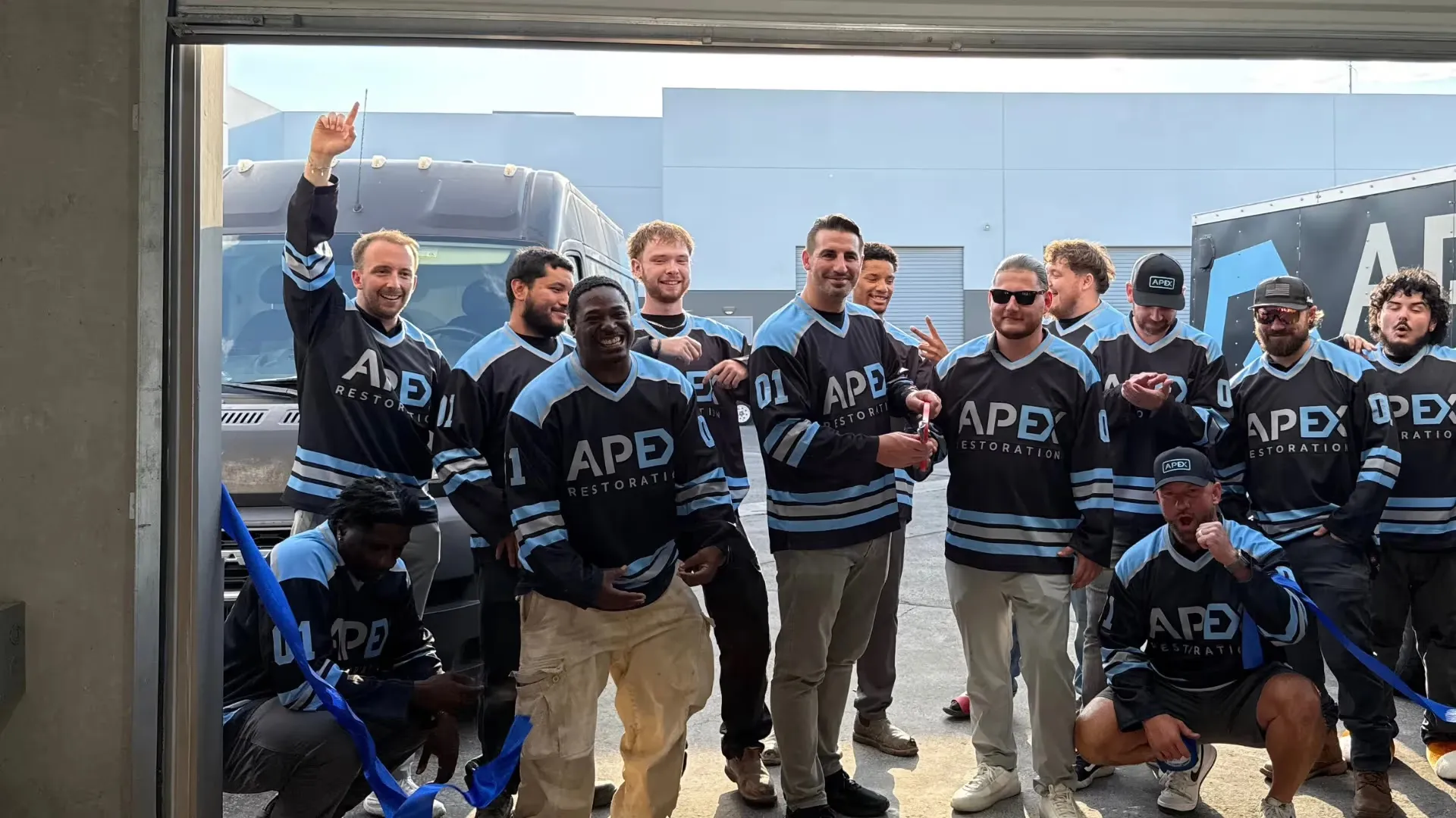The Apex team in matching hockey jerseys at a ribbon cutting, about Apex Home Services, a Las Vegas restoration company