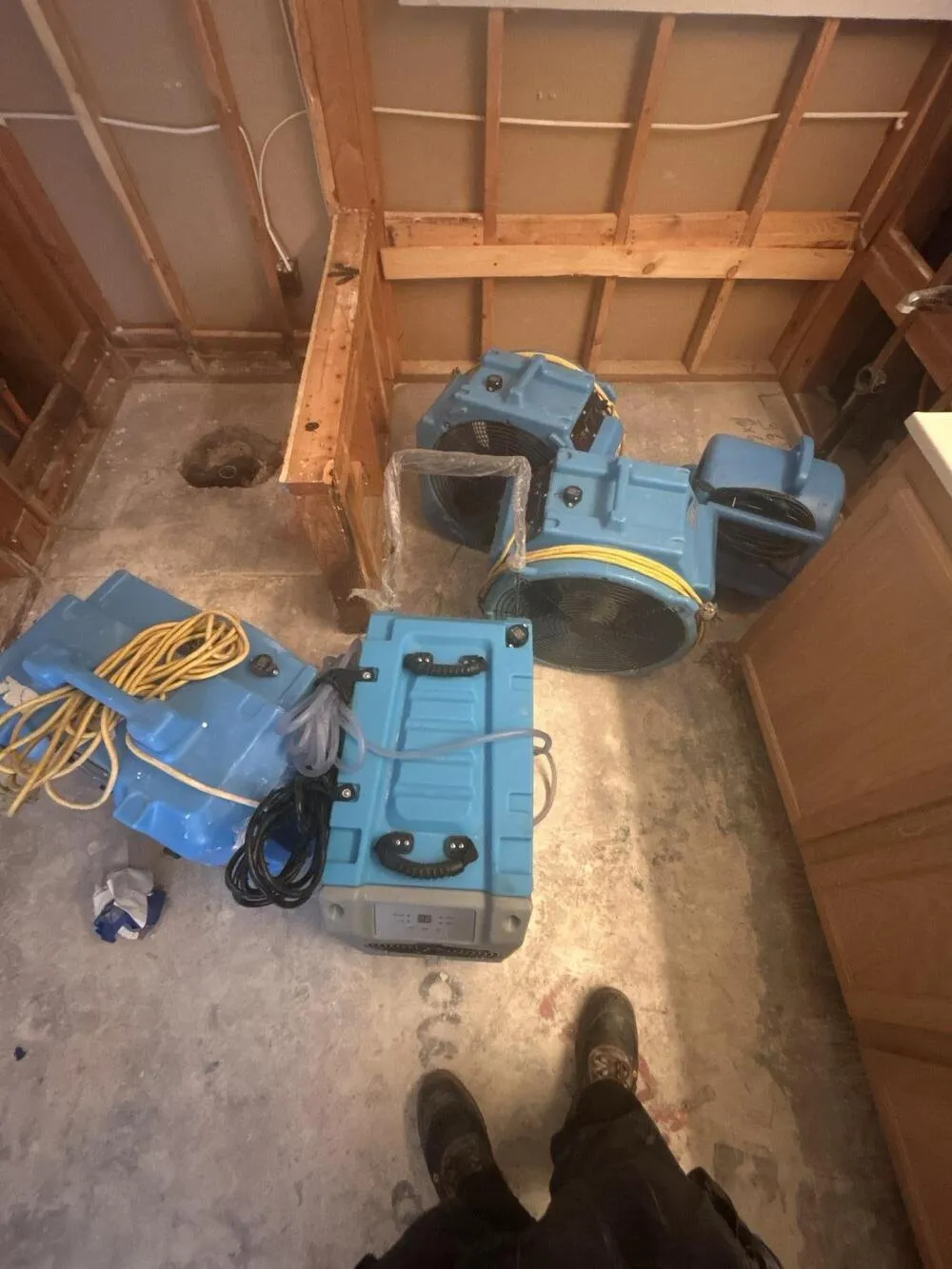 Air movers and a dehumidifier drying a bathroom stripped to the studs, water damage restoration in Paradise, NV