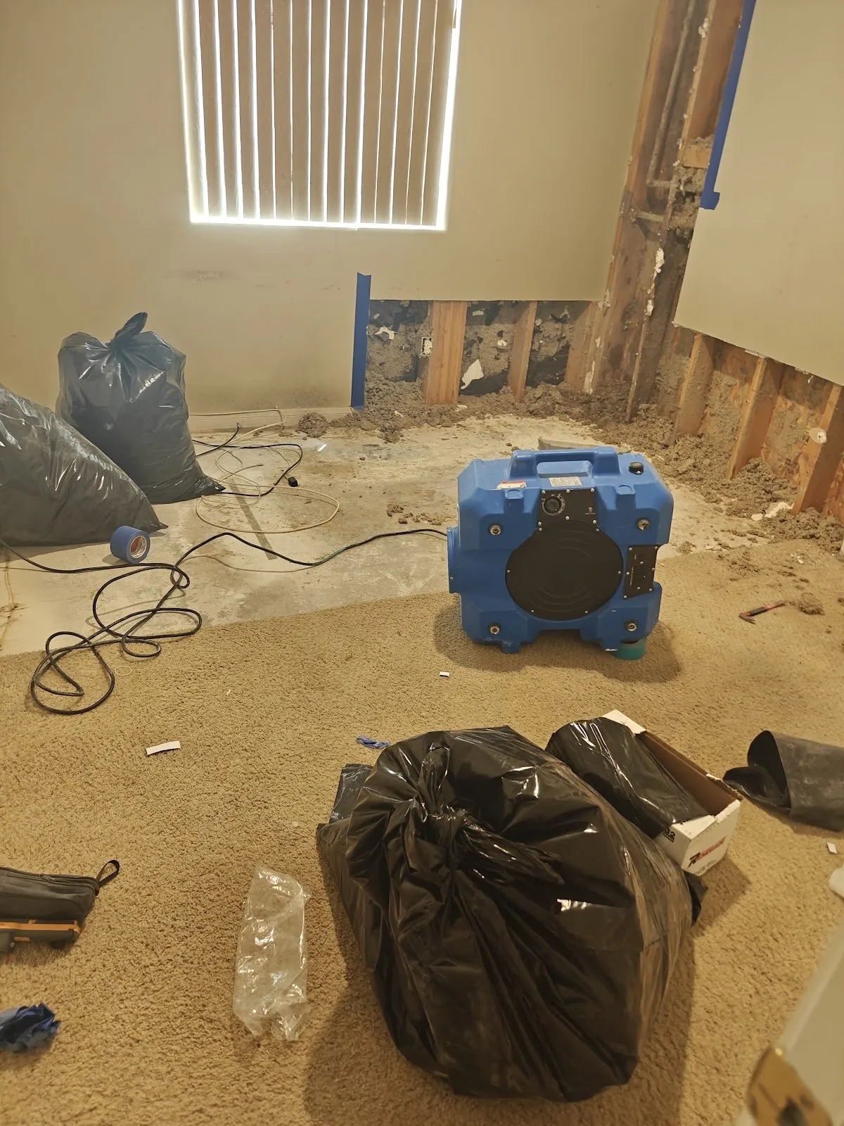 Bedroom with the lower walls cut out, the carpet pulled back and an air scrubber running, water damage restoration in Spring Valley, NV