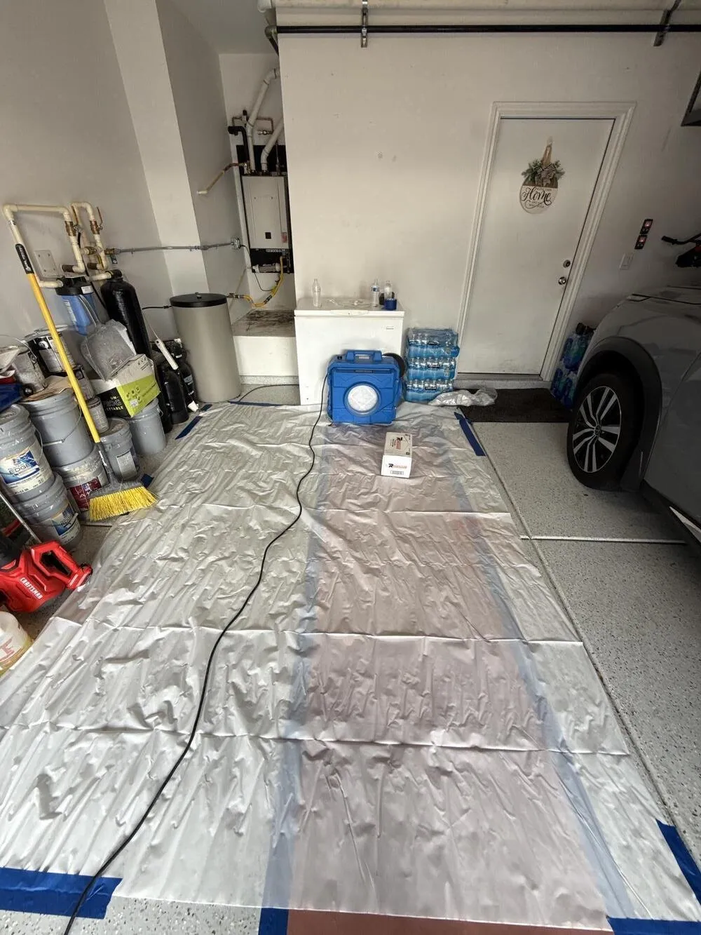 Garage floor covered in protective sheeting with drying equipment set up, water damage restoration in Boulder City, NV