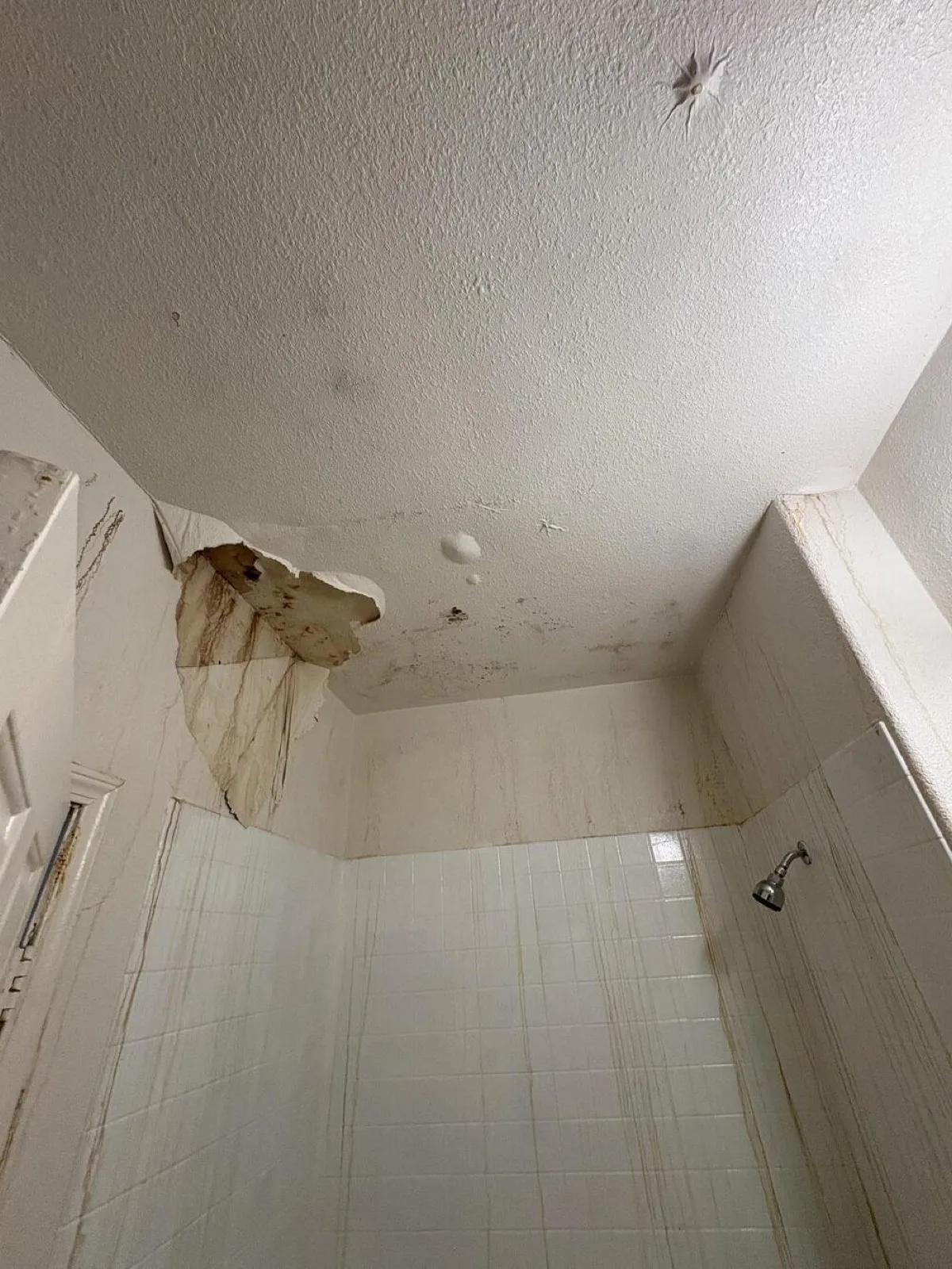 Stained, collapsed patch in a shower ceiling from a leak above, water damage repair in Las Vegas