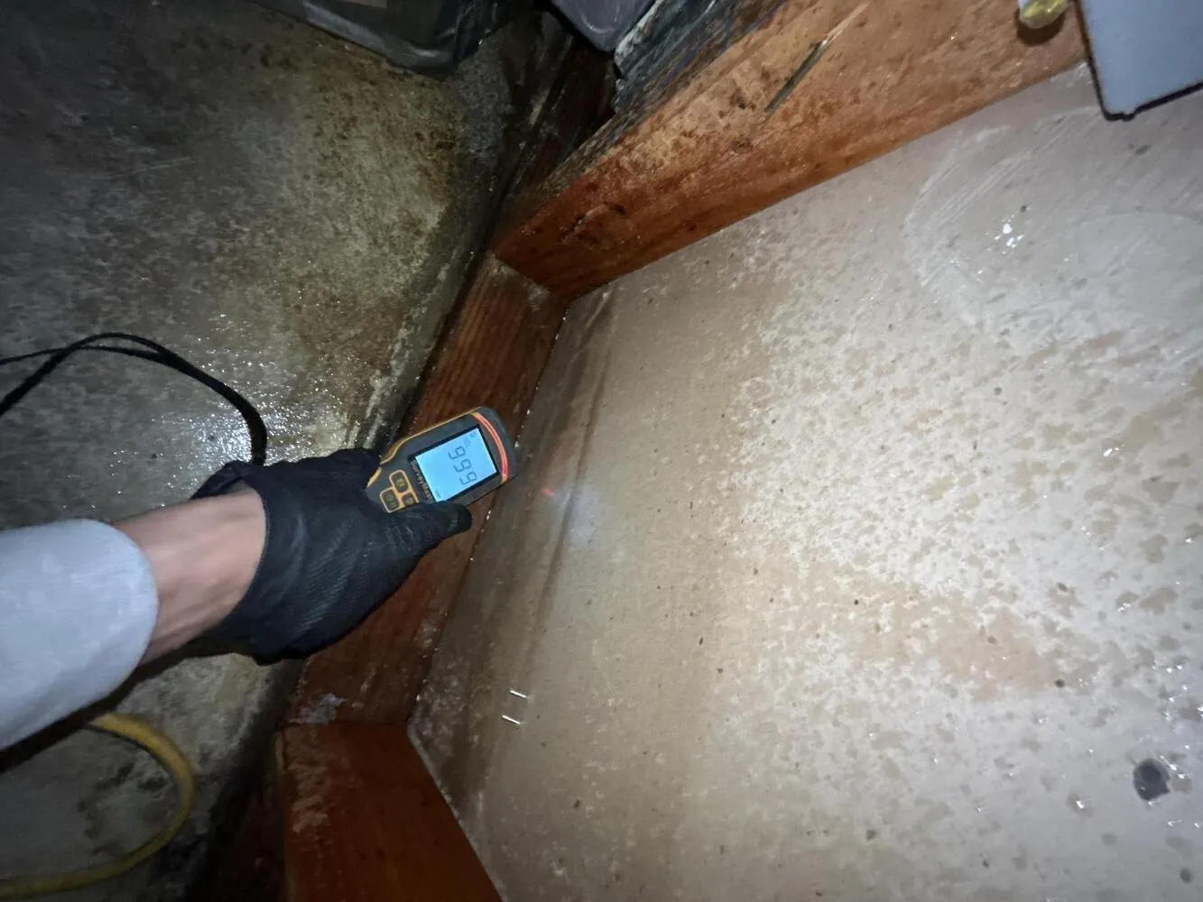 Moisture meter reading on a wet concrete slab beside a wall plate, water damage restoration in Enterprise, NV