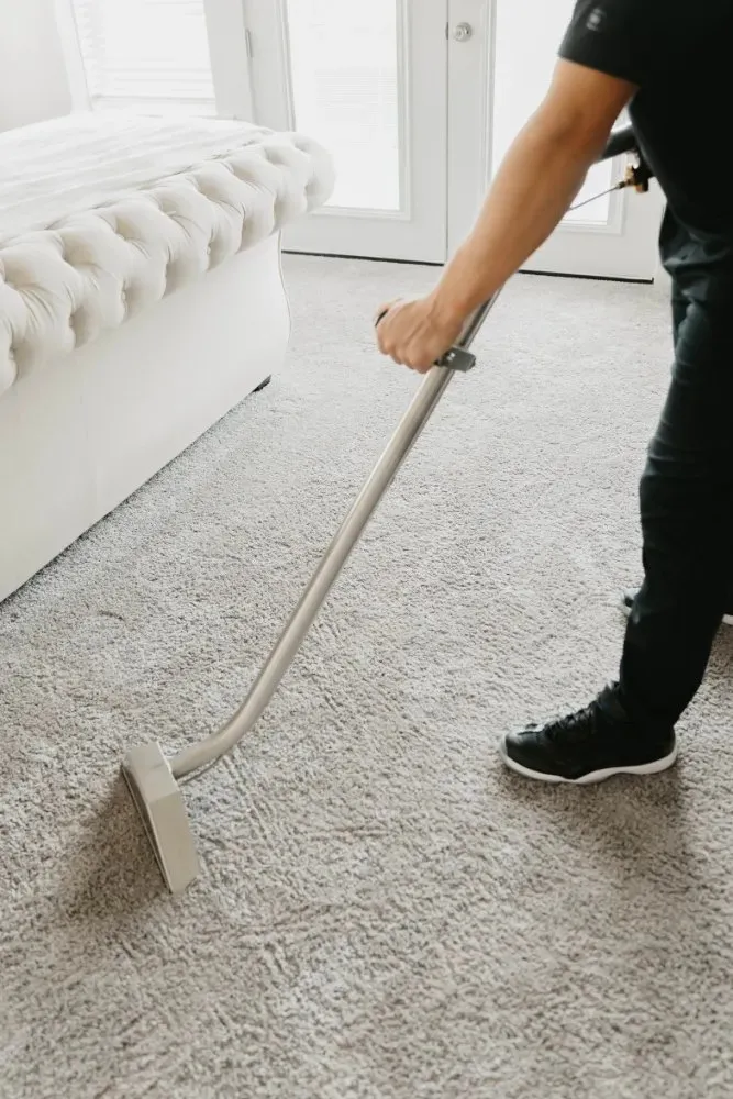 Technician running a water extraction wand over a wet bedroom carpet, water extraction in Las Vegas