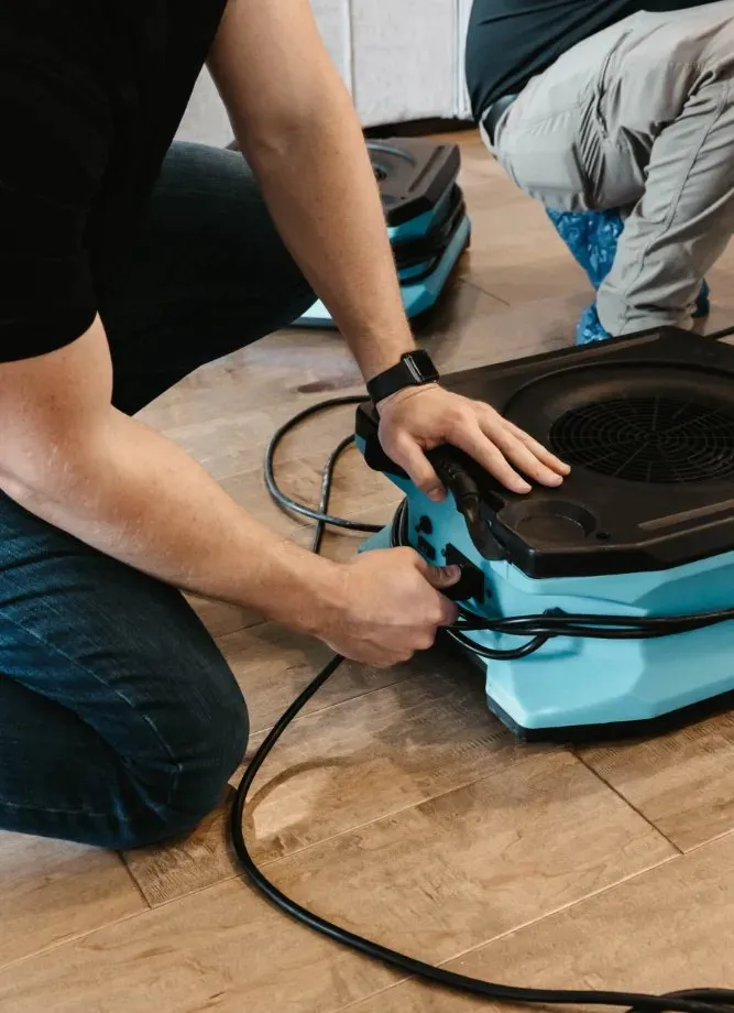Technician plugging in an air mover during drying setup, water damage restoration in Henderson, NV